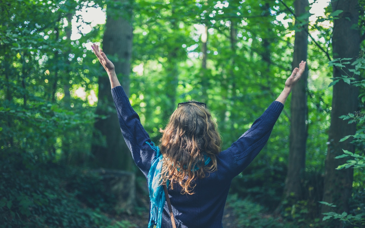 Woman-raising-arms-in-forest-in-British-Columbia